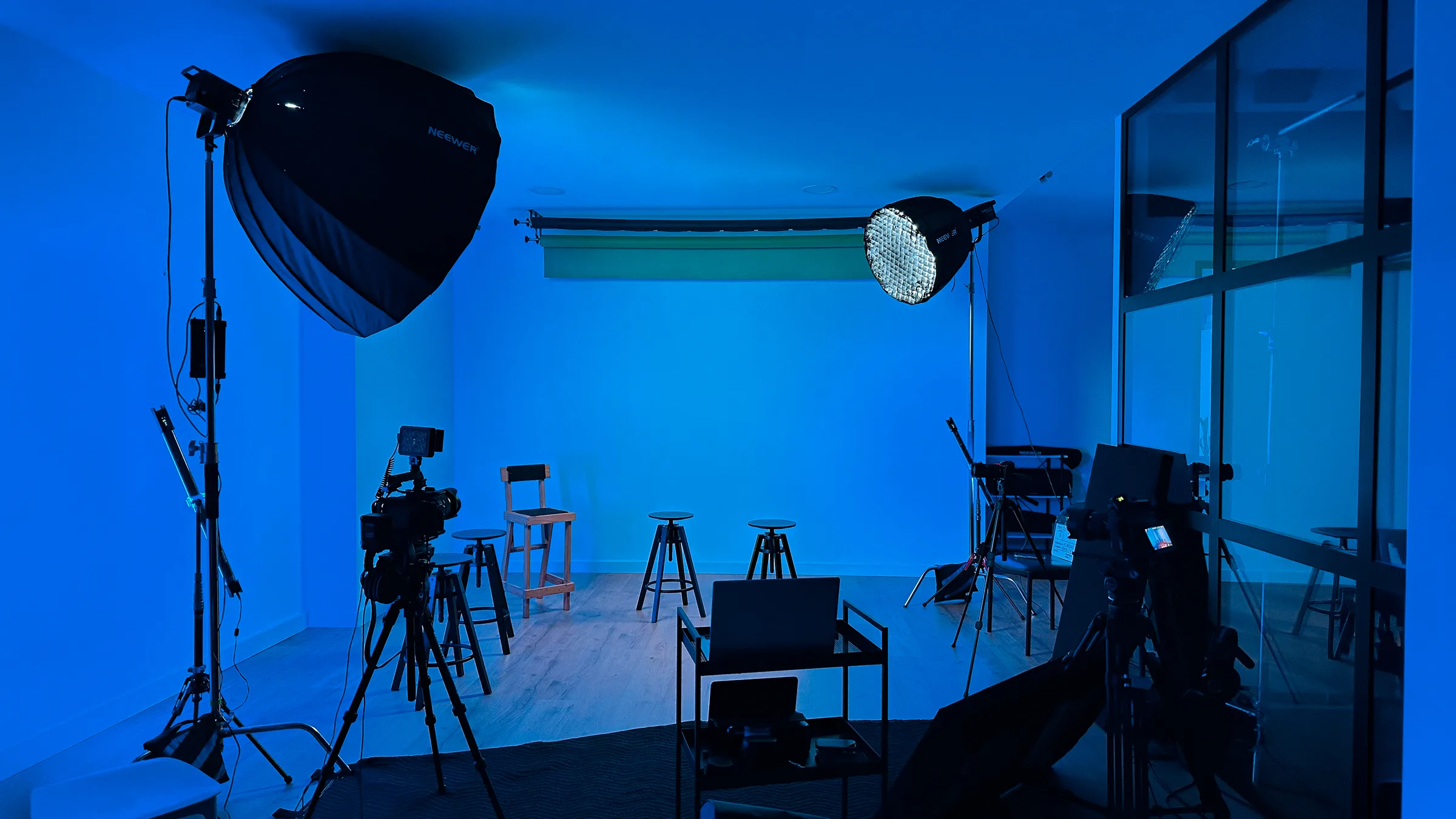 Set de foto y vídeo en el estudio AIRLUSO: softbox Neewer, panel LED redondo, cámaras sobre trípode y ciclorama blanco al fondo.